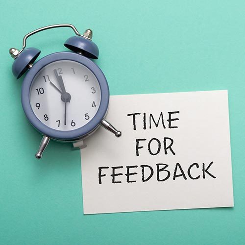 blue alarm clock lies on a blue background next to a card with the text time for feedback. Conceptual business photo on the topic of product evaluation and customer reviews.