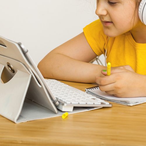 Caucasian girl student wear headphone study online with video call teacher, Happy young girl learning and listening lecture watch write notes look at Tablet PC at home. Covid-19 coronavirus.